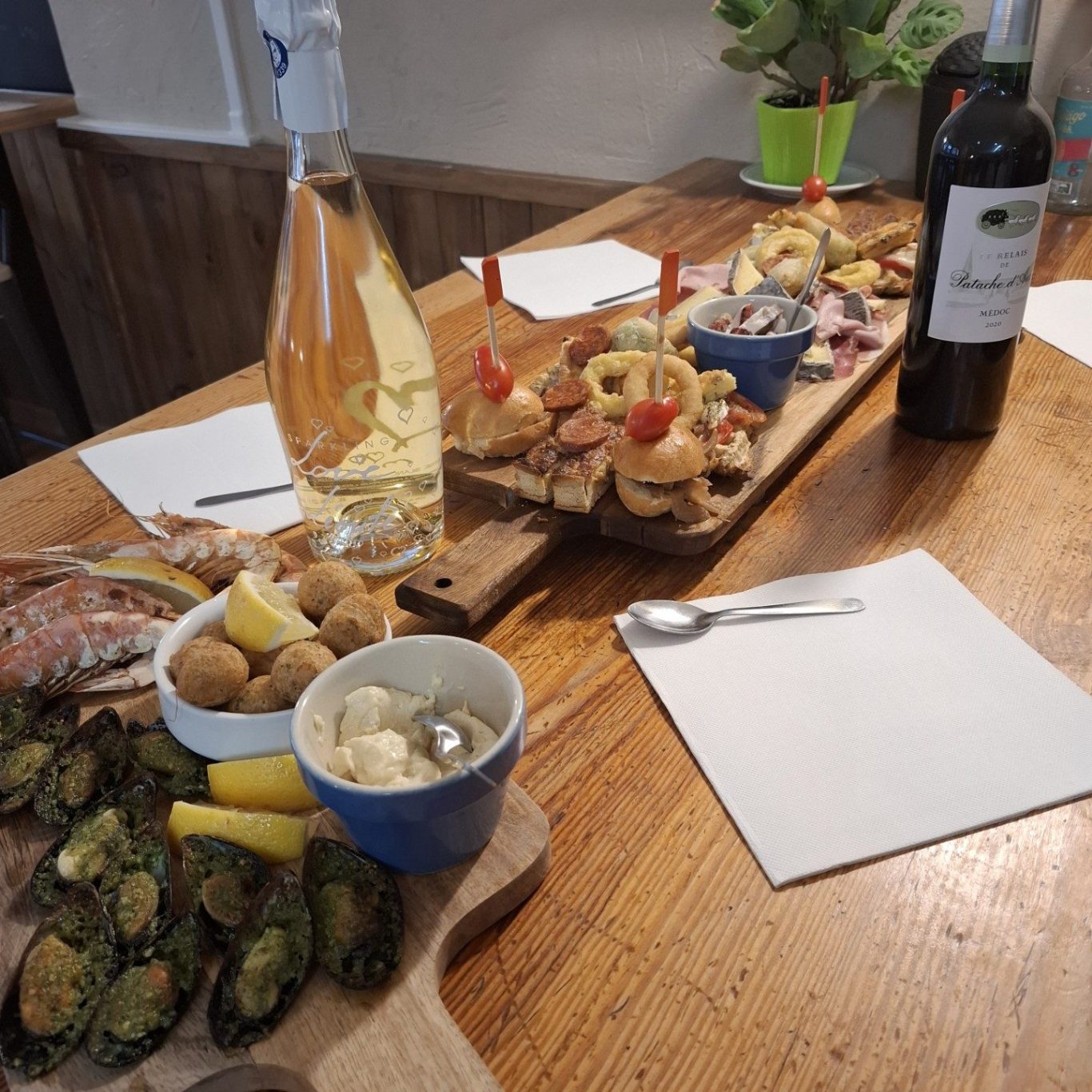 Assiette de tapas variées avec boissons, servie sur une table en bois.